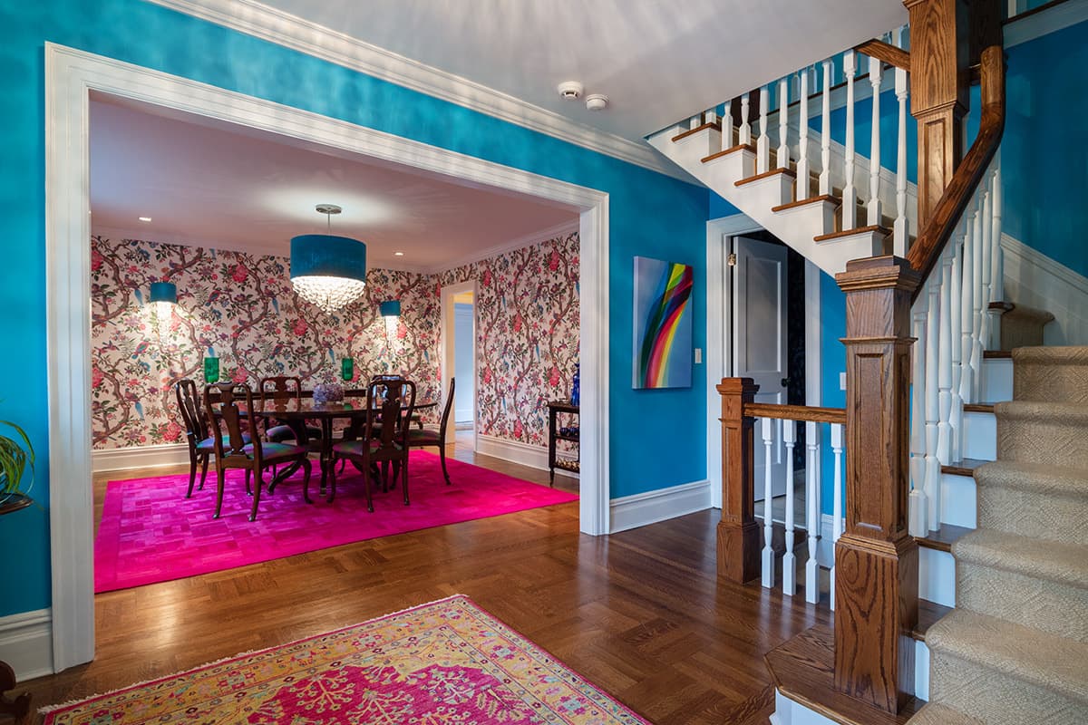 Turquoise stair hall of the brick Georgian in Pelham, with an oak staircase and the floral dining room beyond
