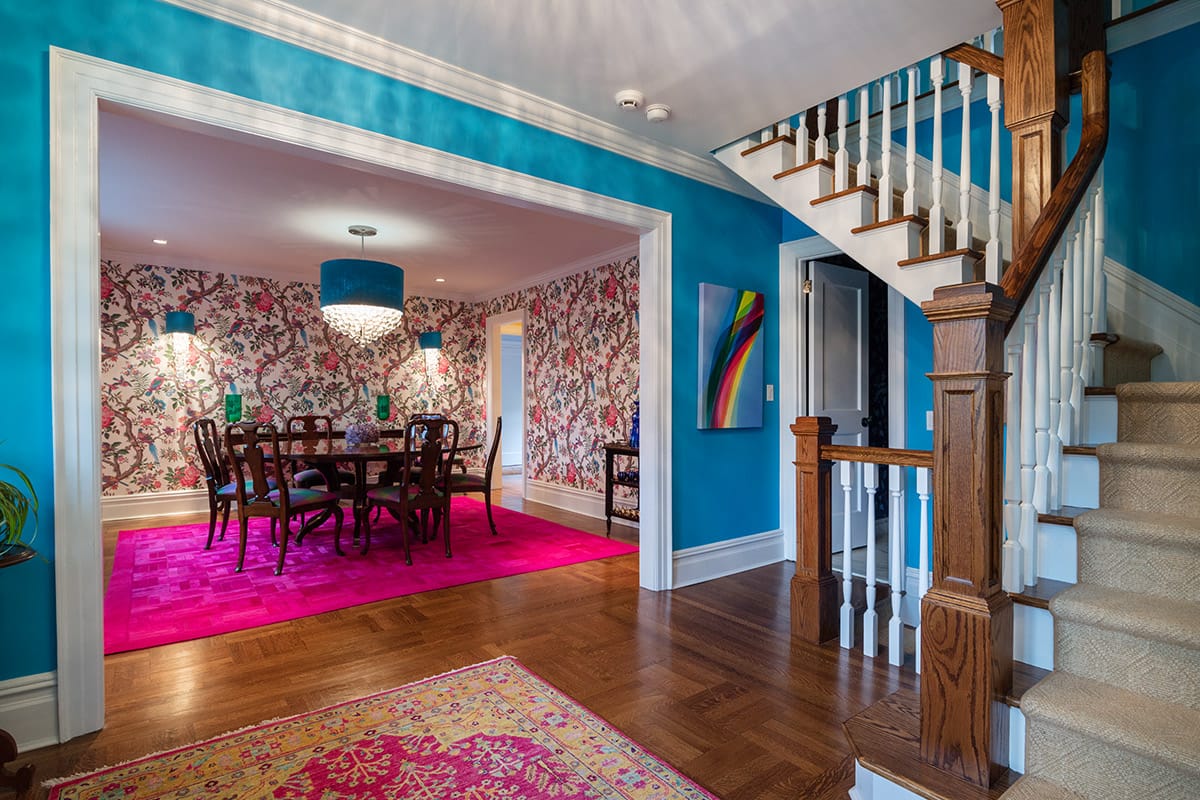 Turquoise stair hall of the brick Georgian with an oak staircase and an opening through to the floral dining room and its magenta rug