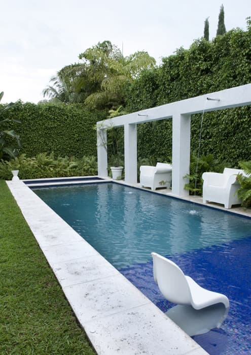 The Rivo Alto Island house lap pool tiled in cobalt, plaster piers with water jets and white moulded chairs standing in the shallows
