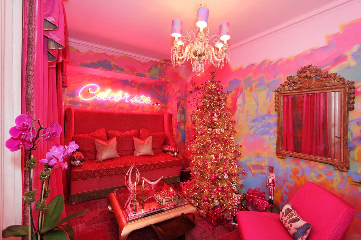 Holiday House show house room in every shade of pink, a neon Celebrate script over the red banquette and a flocked gold tree