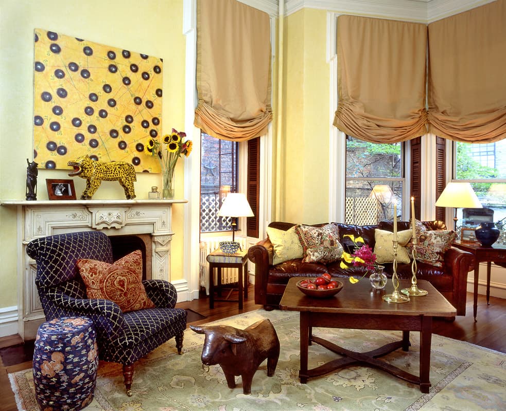Front room of the Gramercy Park townhouse, a leather chesterfield in a bay of three windows under tan balloon shades